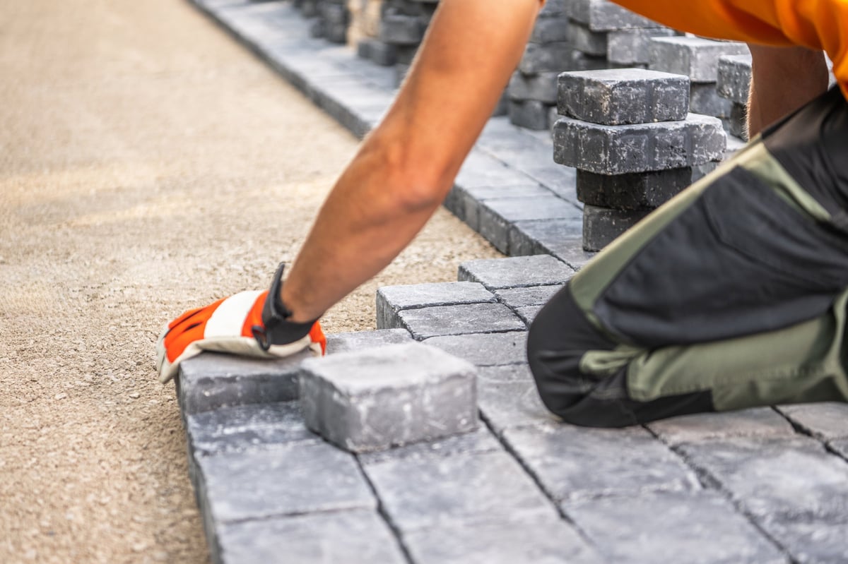 Worker placing paving stones on an outdoor pathway