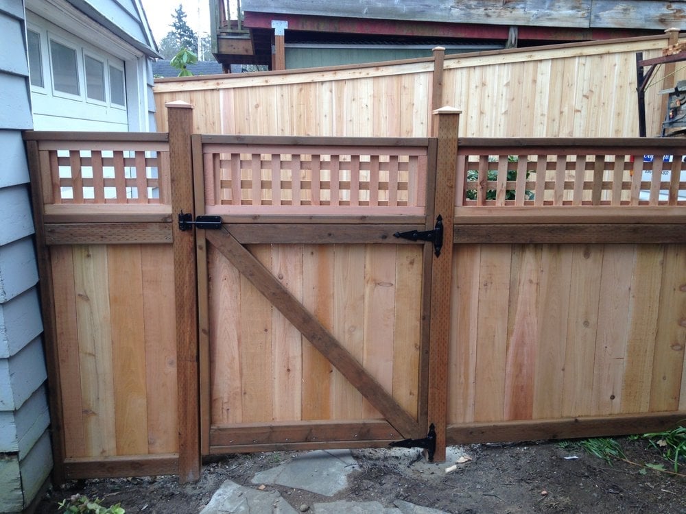 Wooden gate with lattice panels and matching fence sections attached to a residential home exterior